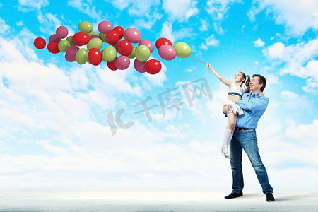 牵着气球摄影照片_父亲牵着女儿的手。幸福的父亲牵着女儿和气球的形象