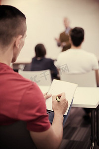 男学生在教室里做笔记。商科教育理念，休闲青年商家研讨会培训