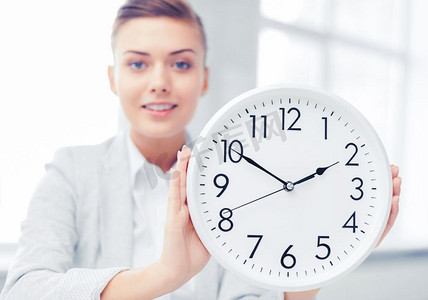 企业、办公室、学校和教育概念-有吸引力的女实业家显示时钟。有吸引力的女商人与白色时钟