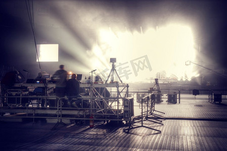 舞台光束背景摄影照片_音乐会前的舞台上闪耀着探照灯的光束。前一阶段