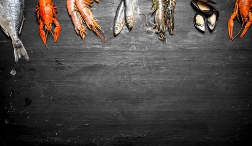 海鲜套餐。各种虾、鱼和贝类。在黑色黑板上..各种虾、鱼和贝类。