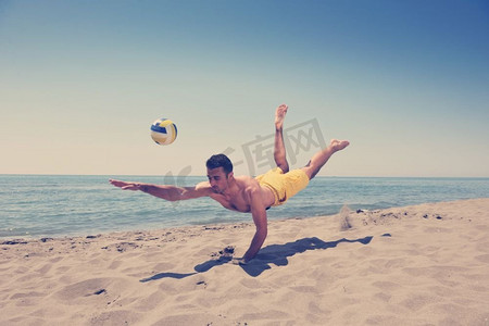 男子沙滩排球运动员在滚烫的沙滩上跳跃