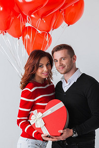 浪漫气球礼物摄影照片_相爱的情侣。幸福地拥抱相爱的情侣，手持情人节礼物和一堆心形气球
