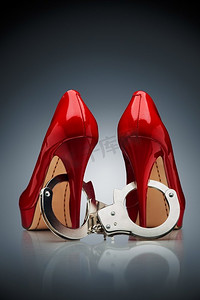 一个美丽的抽象，由两个红色的高跟鞋组成，在白色到银色的渐变背景下戴着手铐。