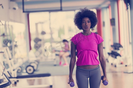 愉快的健康的非洲裔美国妇女在一个crossfit健身房锻炼在重量损失用哑铃.妇女工作出在一个crossfit健身房与哑铃