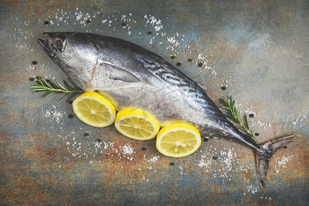 新鲜的鱼与香草香料迷迭香和柠檬/生鱼海鲜在黑板背景顶视图，长尾金枪鱼，东部小金枪鱼