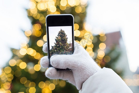 节日、科技和人的概念--用智能手机拍摄圣诞树。用智能手机拍摄圣诞树