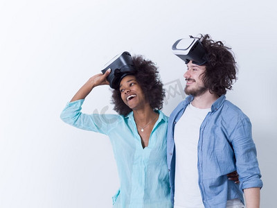 获得使用虚拟现实VR耳机眼镜的经验的愉快的多种族夫妇，在白色背景隔绝