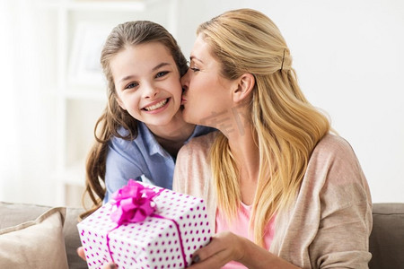 人、假日和家庭概念-给母亲生日礼物的愉快的女孩在家女孩给生日礼物给母亲在家