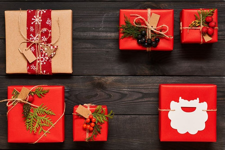 创造性地包装和装饰圣诞节礼物在箱子在黑暗的木背景顶视图从上面.平放。 