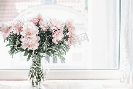 窗台上的玻璃花瓶里有一束美丽的粉色牡丹。室内设计中的花卉。舒适的家。