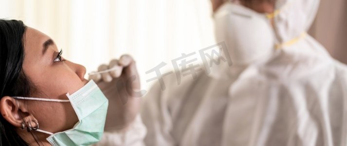 全景医疗人员与PPE套装测试冠状病毒新冠状病毒在医院的亚洲妇女在鼻拭子。COVID—19检测医疗保健概念。