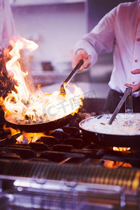 厨师在餐厅的厨房里烹饪和制作食物的火焰。厨师在食物上做火焰弹