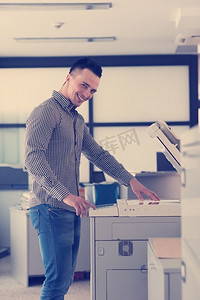年轻的生意人在现代创业公司办公室室内的复印机上复印文件，穿着休闲服