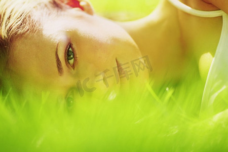 一名妇女近距离躺在草地上。一名妇女躺在草地上
