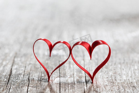 礼物丝带卡摄影照片_两个心形的丝带。两个红色丝带心脏在木backround，情人节概念
