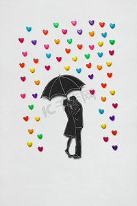 创意情人节概念照片，一对情侣在白色背景下撑着雨伞和雨心。