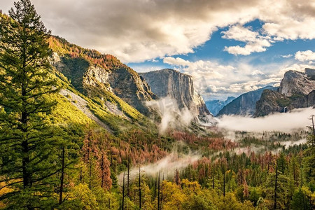 山谷摄影照片_优胜美地国家公园山谷，多云的秋天早晨，从隧道视图。山谷里有低低的云层。美国加利福尼亚州。