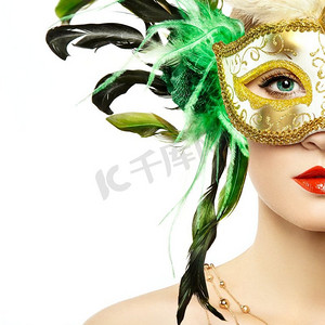 美丽的年轻女子在神秘的金色威尼斯面具。时尚写真。绿色羽毛面具