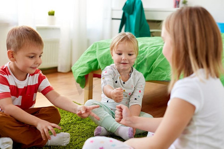 童年、休闲和家庭概念-快乐的小孩子在家里玩石头-剪刀-布游戏。孩子们在家里玩石头剪刀布游戏