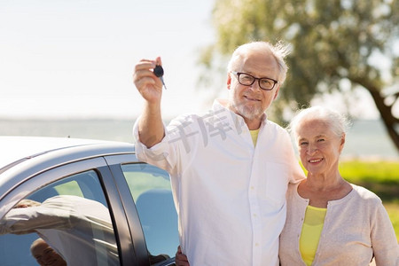公路旅行，旅游和老人概念-幸福的老年夫妇在海边有车钥匙。幸福的高年级夫妇在海边拿着车钥匙