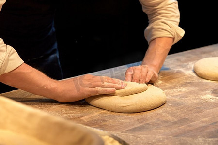 食物烹饪、烘焙和人们的概念--厨师或面包师在面包店制作面团。厨师或面包师在面包店烹调面团