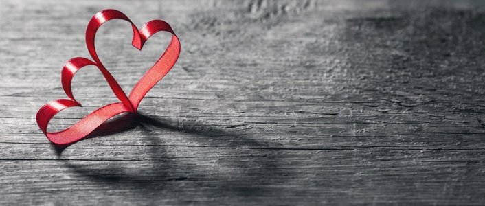 两个心形的丝带。两个红色丝带心脏在木backround，情人节概念