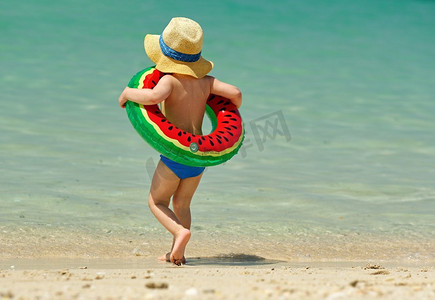 儿童游泳圈摄影照片_海滩上戴着充气游泳圈的两岁幼儿