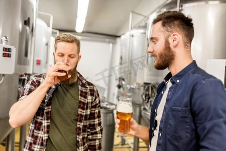 酒精生产、商业和人的概念-男人在啤酒厂饮用和测试精酿啤酒。在酿酒厂饮用和测试精酿啤酒的男子