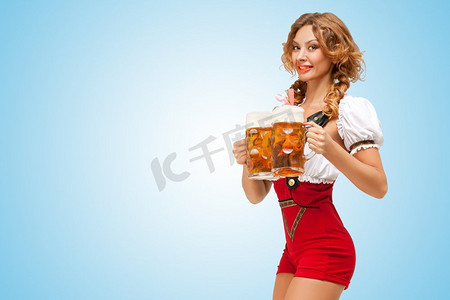 卡通背带裤女孩摄影照片_一名年轻、兴奋、性感的瑞士女子穿着红色连体裤，背带是传统的连衣裙，在蓝色背景上端上了两个啤酒杯。