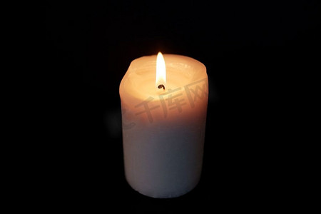 纪念摄影照片_哀悼和纪念的概念-在黑暗中燃烧的蜡烛在黑色的背景上。黑暗中燃烧的蜡烛覆盖着黑色的背景