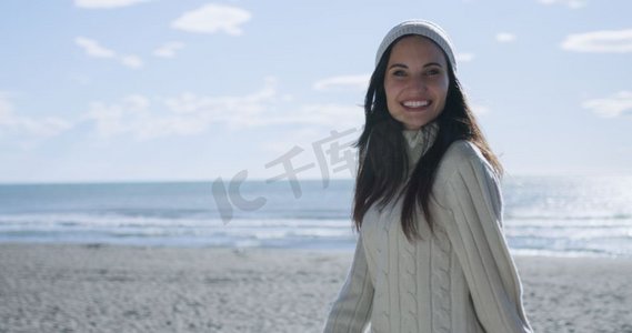一位身着秋装的年轻女子在海滩上微笑