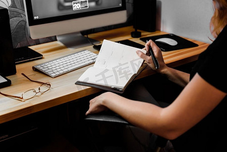 桌子在地毯上摄影照片_工作中的设计师女孩在桌子上画上平板电脑，合上键盘、打印机、电脑