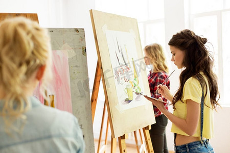 艺术学校、创造力和人概念-有画架、调色板和刷子绘画的妇女在工作室.妇女与画架绘画在艺术学校工作室