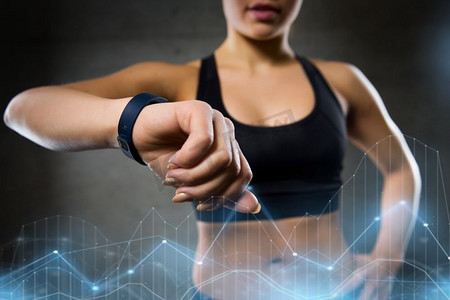 运动、健身、科技和人的概念-年轻女性在健身房看心率。健身房里戴着心率手表的女性