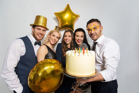 生日蛋糕蛋糕摄影照片_庆祝和节日概念-生日聚会上带着大蛋糕的快乐朋友。生日聚会上带着大蛋糕的快乐朋友