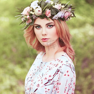 美丽的金发女人头上戴着花环。留着鲜花发型的美女。夏日森林里的女孩。时尚写真