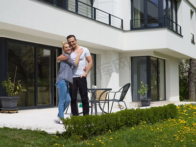 豪华物业摄影照片_一对幸福的年轻夫妇在他们的新豪华别墅前拥抱