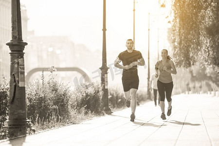 横穿摄影照片_城市运动，健康的年轻夫妇在阳光明媚的早晨在城市中慢跑