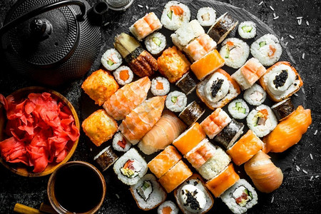 寿司卷配鲑鱼、金枪鱼、蔬菜和虾。在黑暗的乡村背景。寿司卷配鲑鱼、金枪鱼、蔬菜和虾。