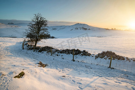 德比郡摄影照片_日出时分，美丽的白雪覆盖着山顶的冬景。风景画。英国山顶地区日出时分白雪覆盖的冬季景观