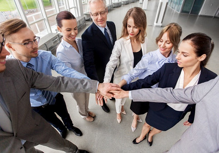 企业、人员和团队合作的概念—快乐的业务团队在办公室堆叠双手。快乐的生意人堆叠在办公室的手