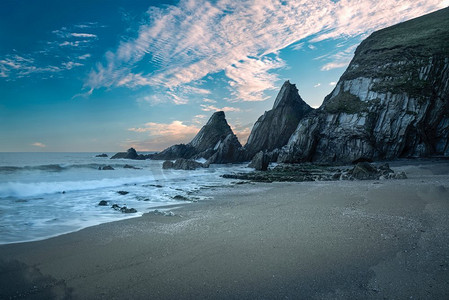 美丽的五颜六色的日落笼罩着锯齿状岩层的海滩景观