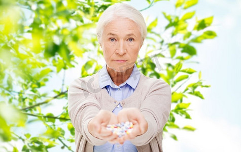 不吃药摄影照片_年龄、保健和医学概念-绿色自然背景下服用药物的老年女性。在家吃药的老年妇女