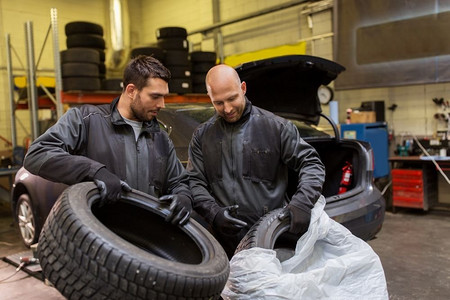 汽车保养、维修、保养、以人为本--两位汽车技师在车间换轮胎。汽车修理工在车间更换汽车轮胎