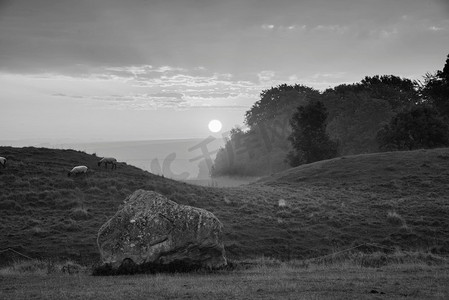英国乡村新石器时代矗立的石碑上美丽的黑白夏日日出景观，绚丽的灯光和背景雾