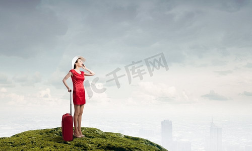 穿红衣服的女人。一位身穿红色连衣裙、背着红色行李箱的年轻女子正在用手机交谈