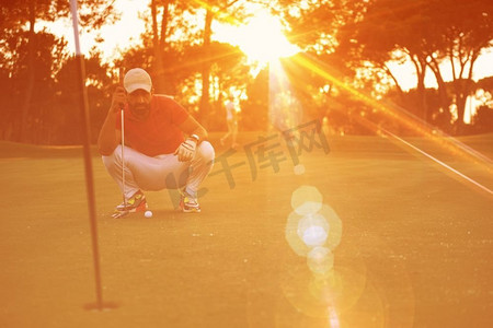 高尔夫球手在美丽的日落中用球杆瞄准射击，背景是太阳耀眼。高尔夫球手在美丽的日落上完美射门
