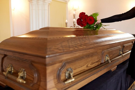 红玫瑰摄影照片_人和哀悼的概念-教堂葬礼上手持红玫瑰和棺材的女人。葬礼上手持红玫瑰和棺材的女子