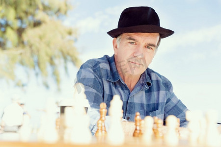 坐在户外下棋的老人。对象棋策略的思考
